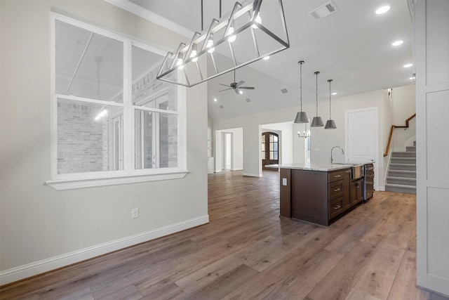 kitchen with decorative light fixtures, a center island with sink, and wood-type flooring