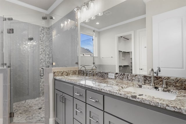 bathroom featuring a shower with shower door, ornamental molding, dual sinks, and vanity with extensive cabinet space