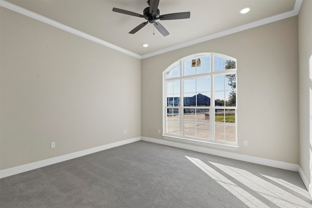 spare room with dark carpet, ornamental molding, ceiling fan, and a wealth of natural light