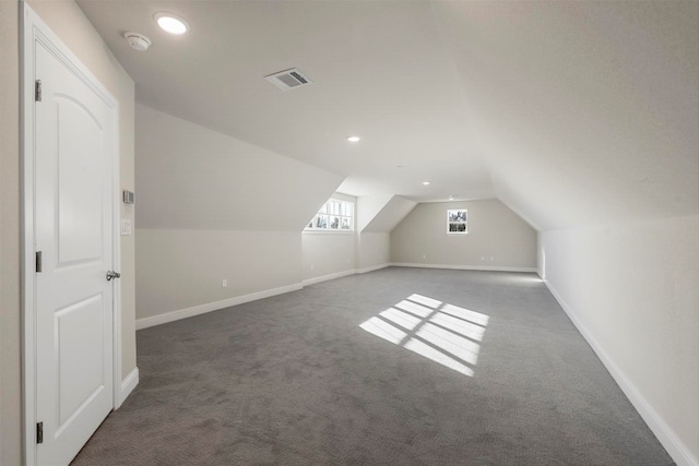 bonus room with vaulted ceiling and dark colored carpet