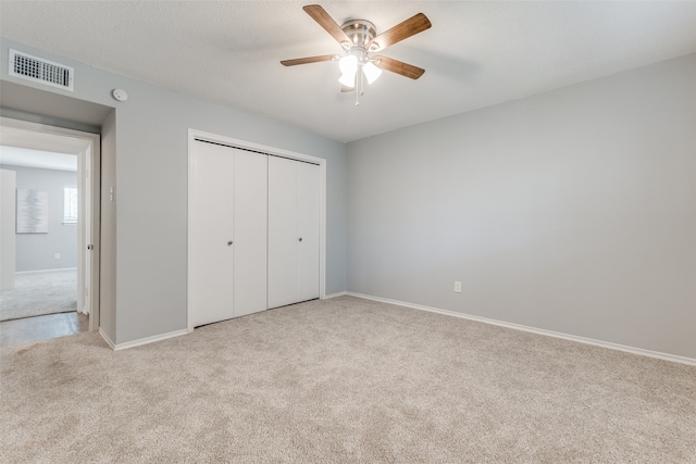 unfurnished bedroom with light carpet, a closet, and ceiling fan