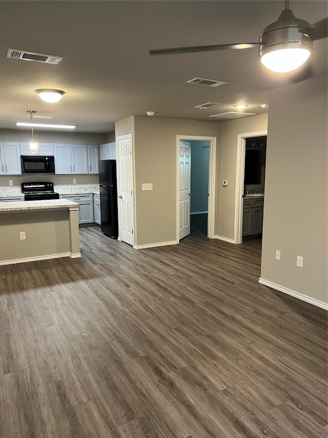 kitchen with black appliances, dark hardwood / wood-style floors, light stone counters, and pendant lighting