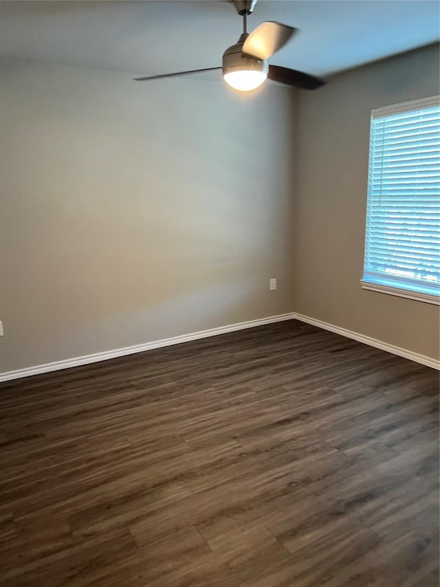 empty room featuring a ceiling fan, dark wood finished floors, and baseboards