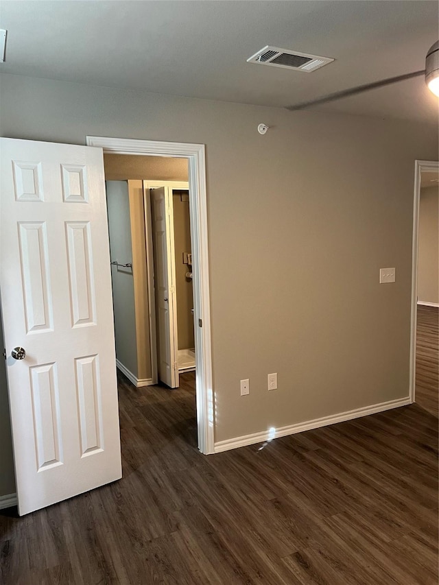 unfurnished room featuring visible vents, dark wood finished floors, and baseboards