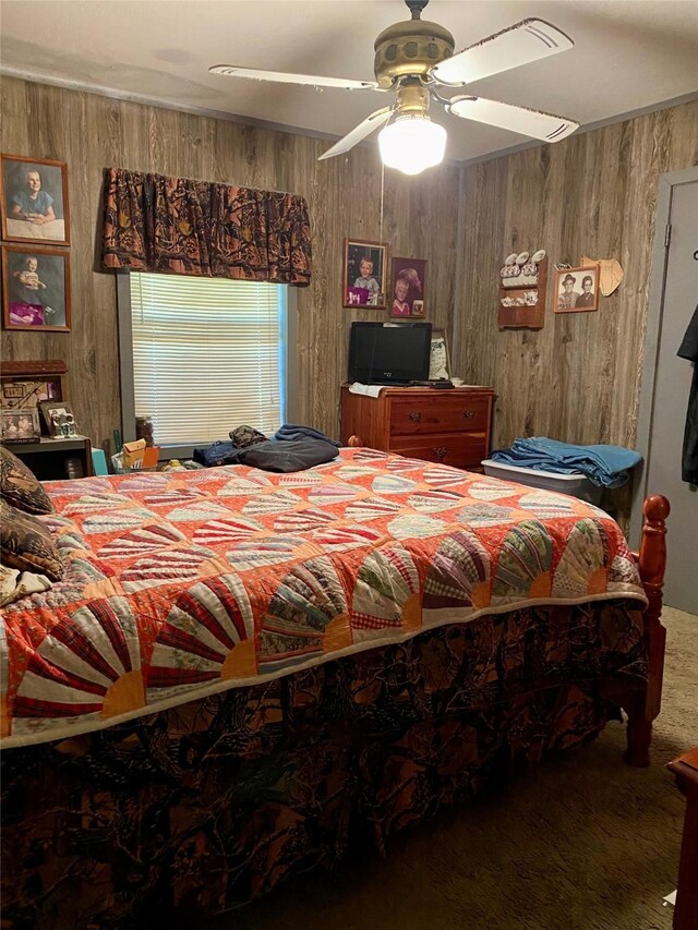 carpeted bedroom featuring ceiling fan and wood walls