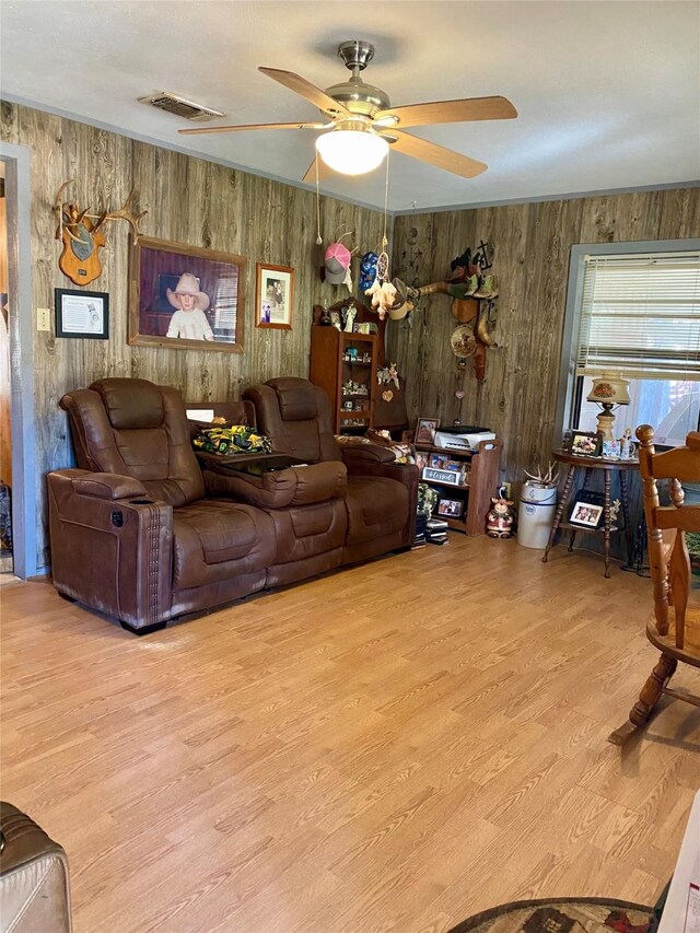 living room featuring light hardwood / wood-style flooring, ceiling fan, and wooden walls