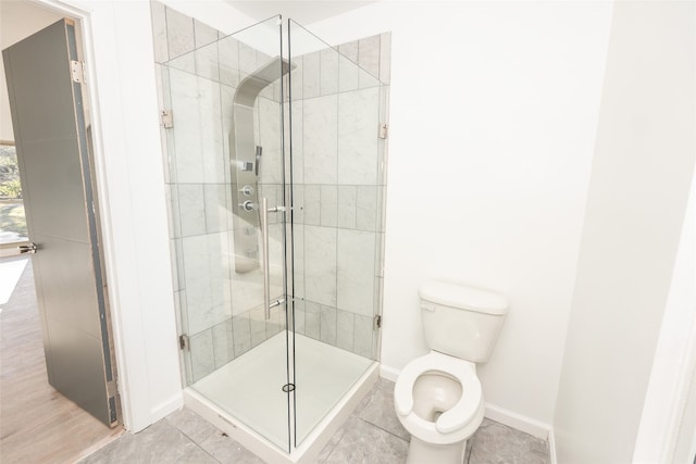 bathroom featuring toilet, tile flooring, and a shower with door