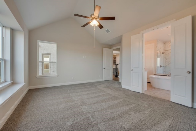 unfurnished bedroom featuring ensuite bathroom, ceiling fan, light colored carpet, and lofted ceiling