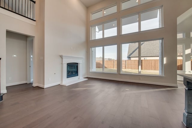 unfurnished living room with a high ceiling and hardwood / wood-style flooring