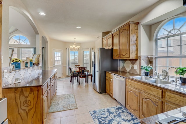 kitchen with hanging light fixtures, stainless steel appliances, a chandelier, tasteful backsplash, and light tile floors