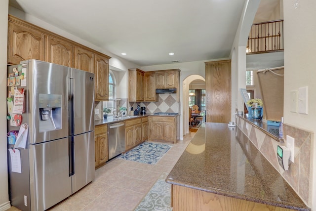 kitchen featuring stone counters, appliances with stainless steel finishes, sink, light tile floors, and tasteful backsplash