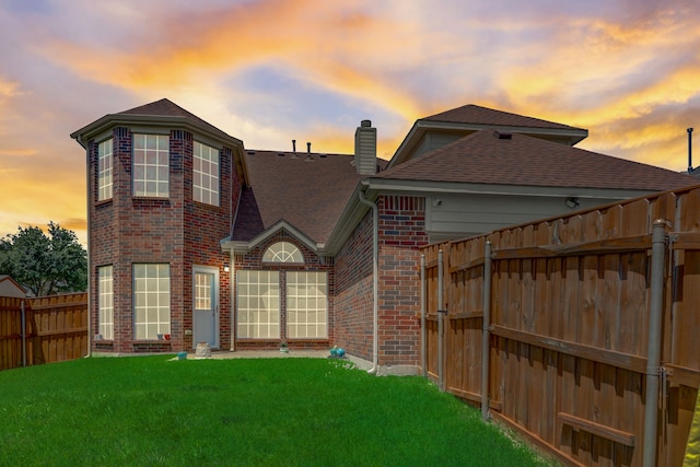 back house at dusk with a lawn