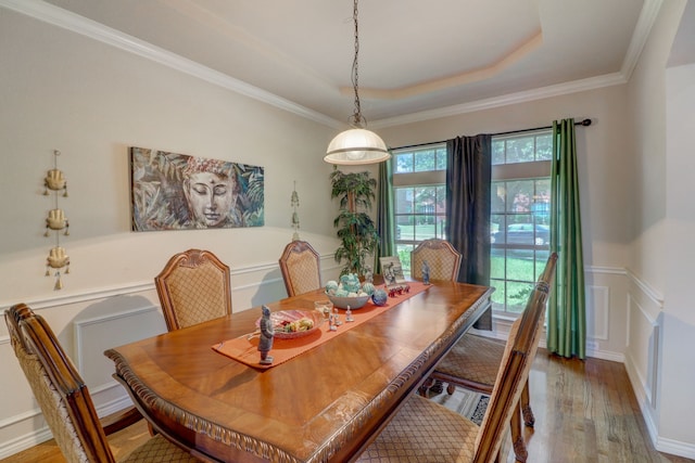 dining area with ornamental molding, wood-type flooring, and a tray ceiling