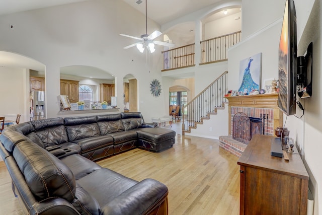 living room with plenty of natural light, high vaulted ceiling, ceiling fan, and light hardwood / wood-style floors