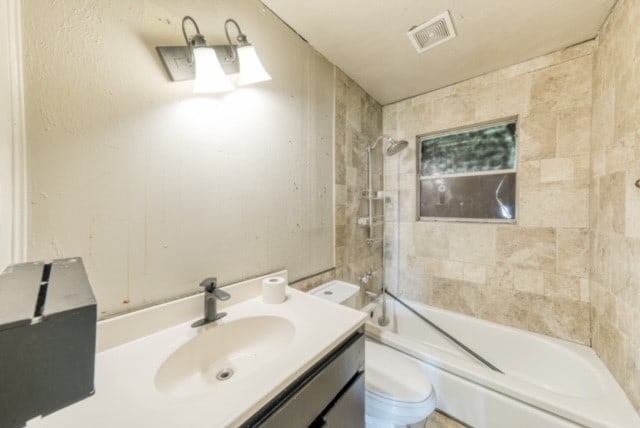 full bathroom with vanity, tiled shower / bath combo, and toilet