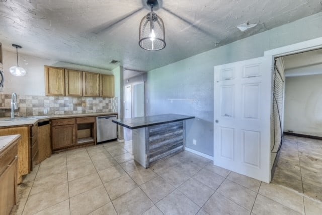 kitchen with pendant lighting, sink, light tile patterned floors, dishwasher, and backsplash