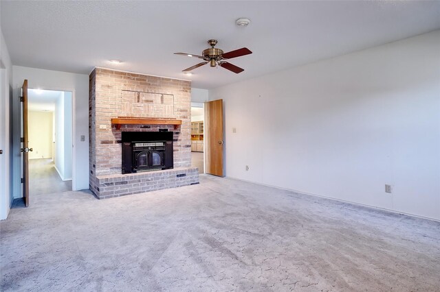 unfurnished living room with carpet flooring, a wood stove, and ceiling fan