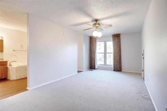 spare room featuring light carpet, a textured ceiling, and ceiling fan