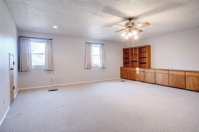 carpeted spare room featuring ceiling fan, a textured ceiling, and a wealth of natural light