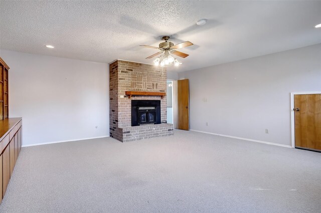 unfurnished living room with carpet, a textured ceiling, ceiling fan, and a fireplace