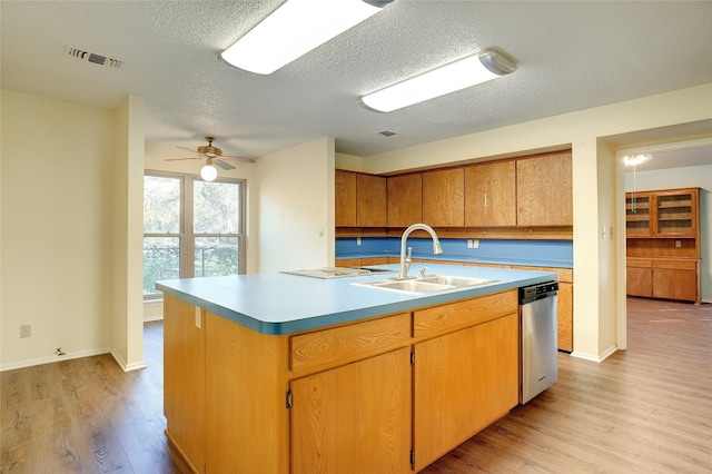 kitchen with dishwasher, a center island with sink, sink, ceiling fan, and light wood-type flooring