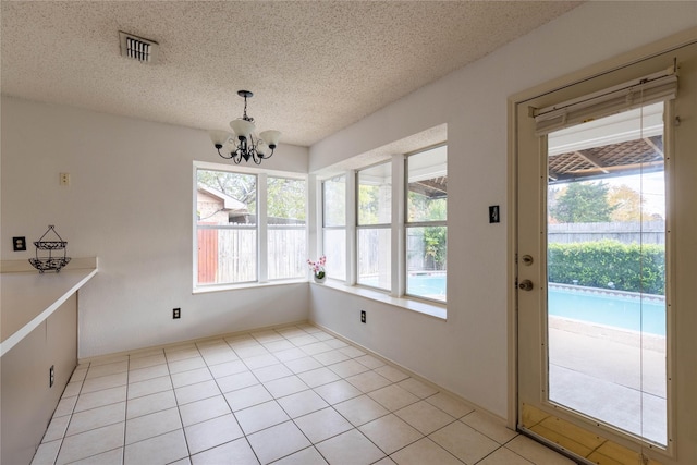 unfurnished dining area featuring a textured ceiling, a notable chandelier, and light tile patterned flooring