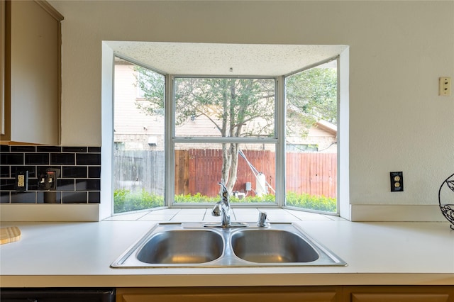 kitchen with decorative backsplash, sink, and dishwashing machine