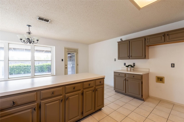 kitchen with a textured ceiling, decorative light fixtures, an inviting chandelier, and light tile patterned flooring