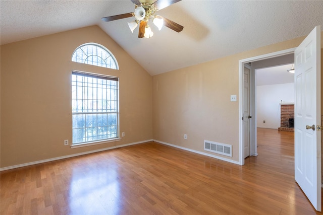 spare room featuring a textured ceiling, ceiling fan, light hardwood / wood-style flooring, and vaulted ceiling