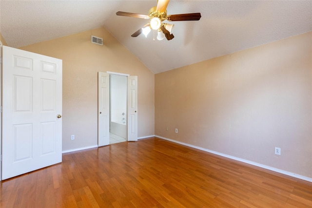 unfurnished bedroom with ceiling fan, wood-type flooring, a textured ceiling, and vaulted ceiling