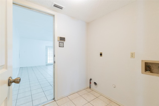 clothes washing area with electric dryer hookup, hookup for a gas dryer, hookup for a washing machine, a textured ceiling, and light tile patterned flooring