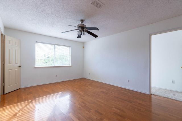 empty room with hardwood / wood-style floors, ceiling fan, and a textured ceiling