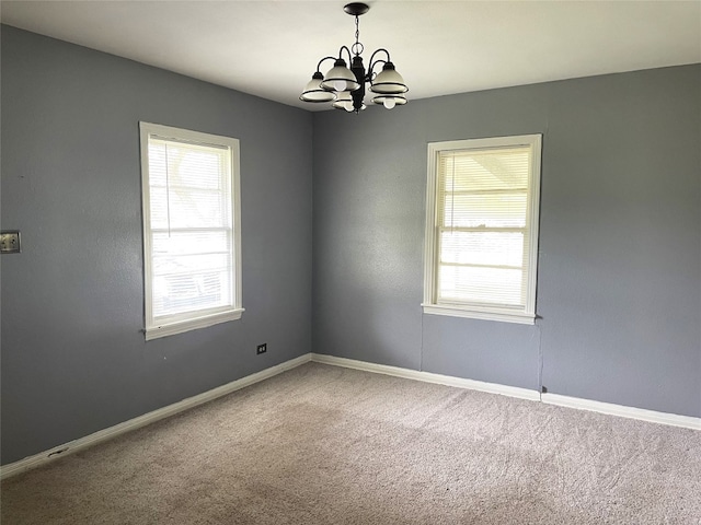 carpeted empty room with a chandelier and a wealth of natural light