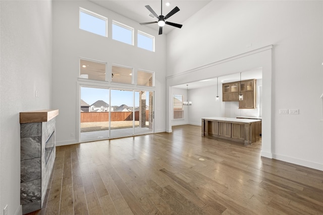 unfurnished living room with ceiling fan with notable chandelier, dark hardwood / wood-style floors, and a towering ceiling