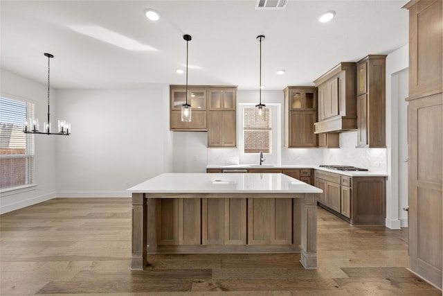 kitchen featuring light hardwood / wood-style flooring, hanging light fixtures, a notable chandelier, and a kitchen island