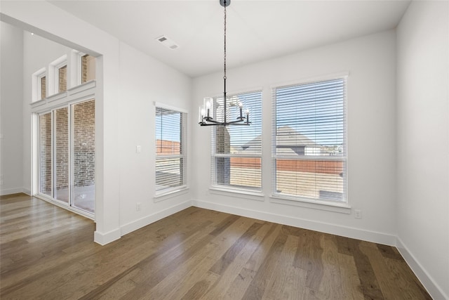 unfurnished dining area with dark hardwood / wood-style flooring and a chandelier