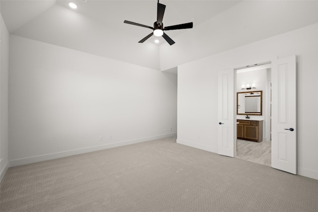 unfurnished bedroom featuring light colored carpet, connected bathroom, vaulted ceiling, and ceiling fan