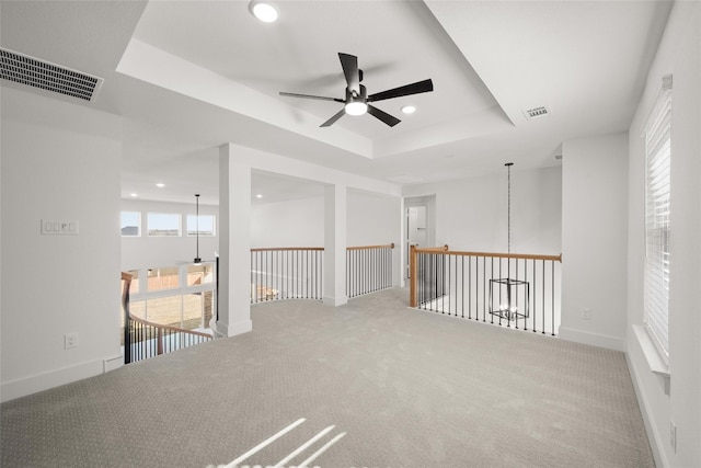 empty room featuring carpet, a raised ceiling, and ceiling fan with notable chandelier