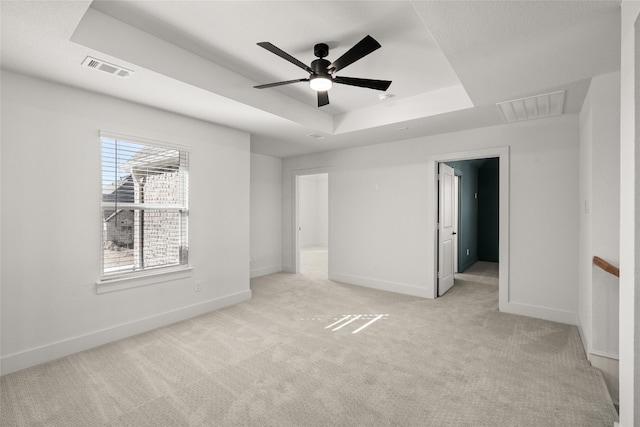 carpeted spare room featuring a raised ceiling and ceiling fan