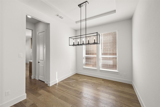 unfurnished room with an inviting chandelier and dark hardwood / wood-style flooring