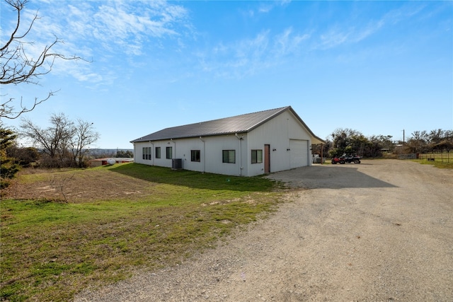 view of side of property featuring a yard, a garage, and central air condition unit