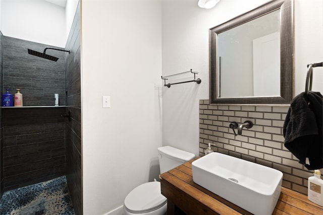 bathroom with vanity, toilet, and tiled shower