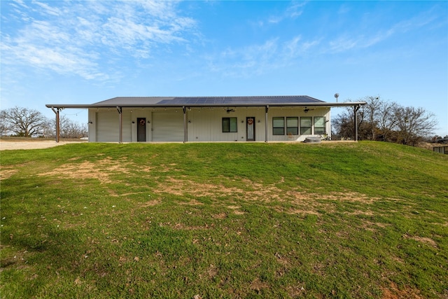 rear view of property with covered porch, a garage, and a lawn