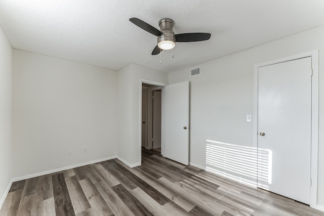 empty room with wood-type flooring, a textured ceiling, and ceiling fan