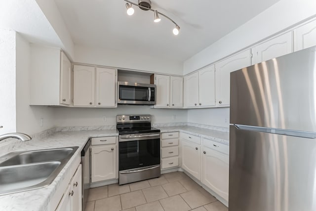 kitchen featuring white cabinetry, sink, light tile patterned floors, and appliances with stainless steel finishes