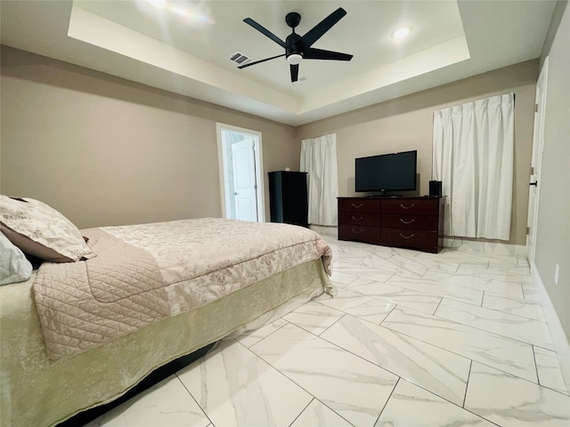 bedroom featuring light tile patterned floors, ceiling fan, and a raised ceiling