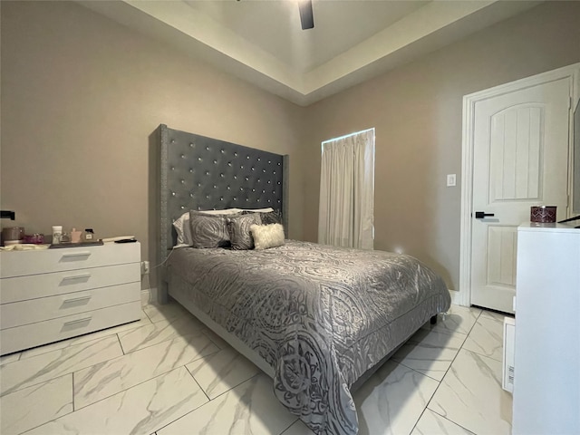 tiled bedroom featuring a tray ceiling and ceiling fan