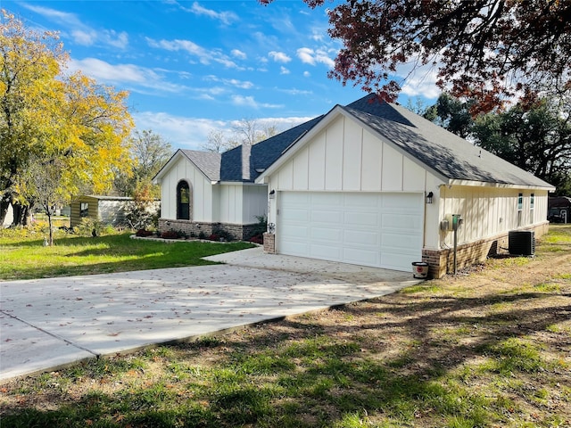 view of front of house featuring central air condition unit, a garage, and a front yard