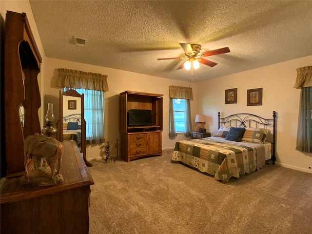 carpeted bedroom featuring ceiling fan and a textured ceiling