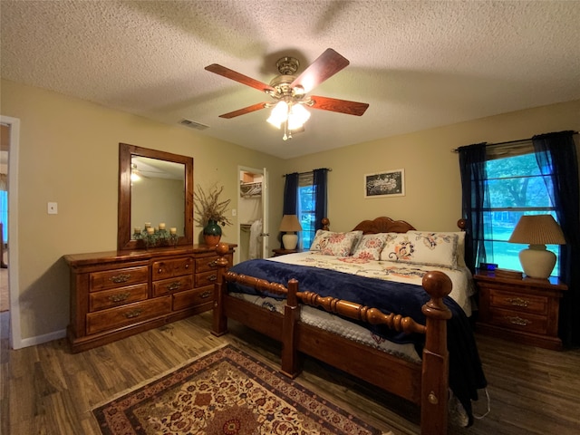 bedroom featuring ceiling fan, dark wood-type flooring, a textured ceiling, and a spacious closet